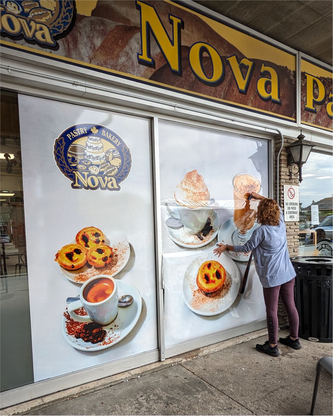 Professional installation of a full-coverage solid window wrap for Nova Bakery featuring high-resolution food branding.