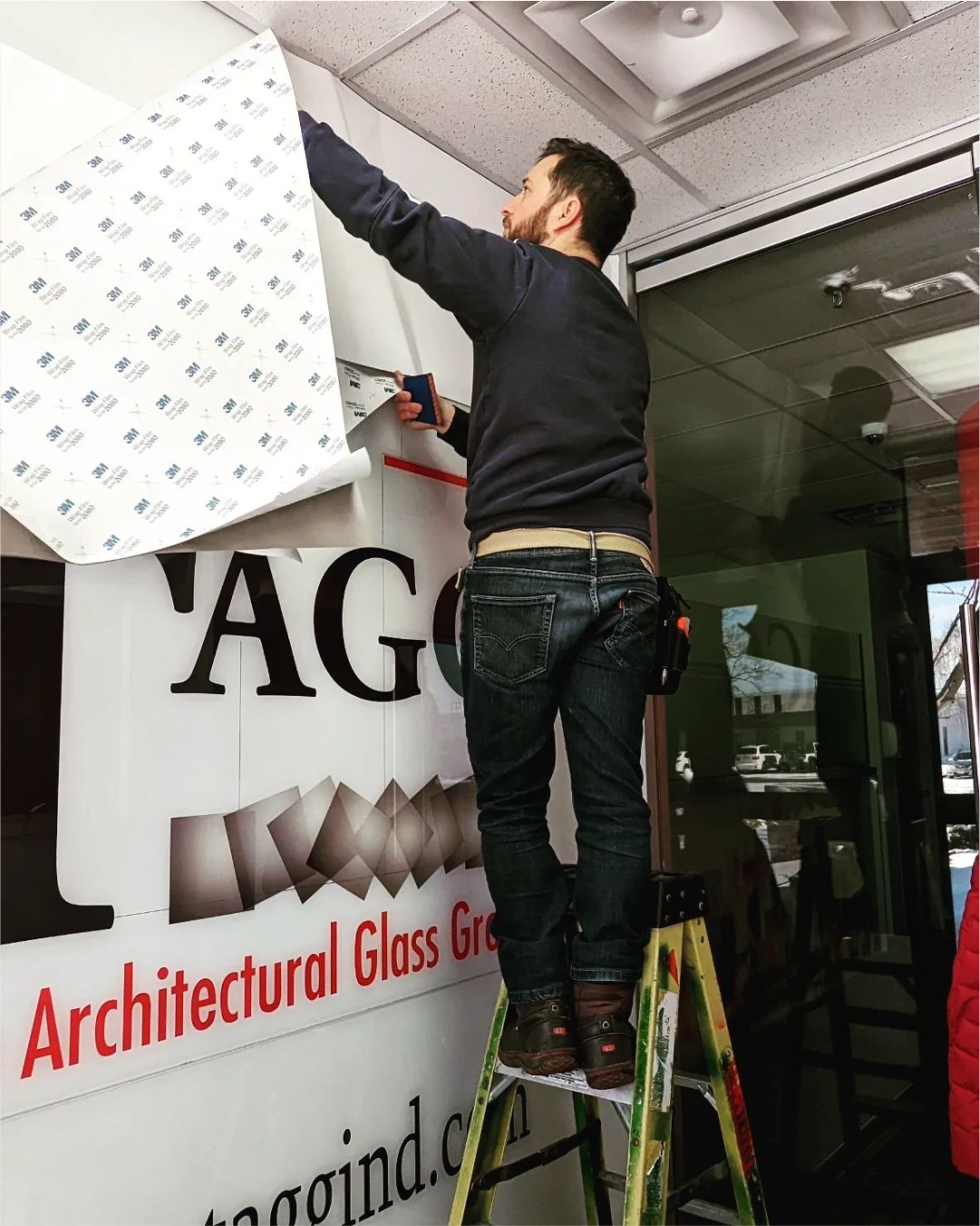 Professional installation of a large-format brand mural for Architectural Glass Group using premium 3M wrap film.